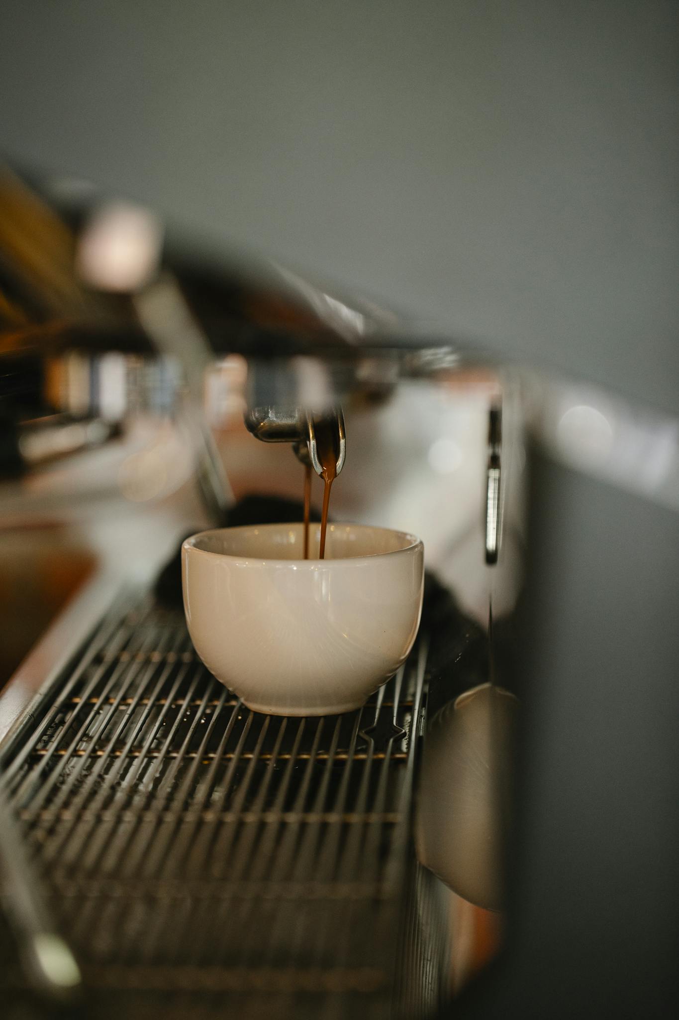 Modern coffee machine preparing double shot espresso pouring in white ceramic cup in cafe