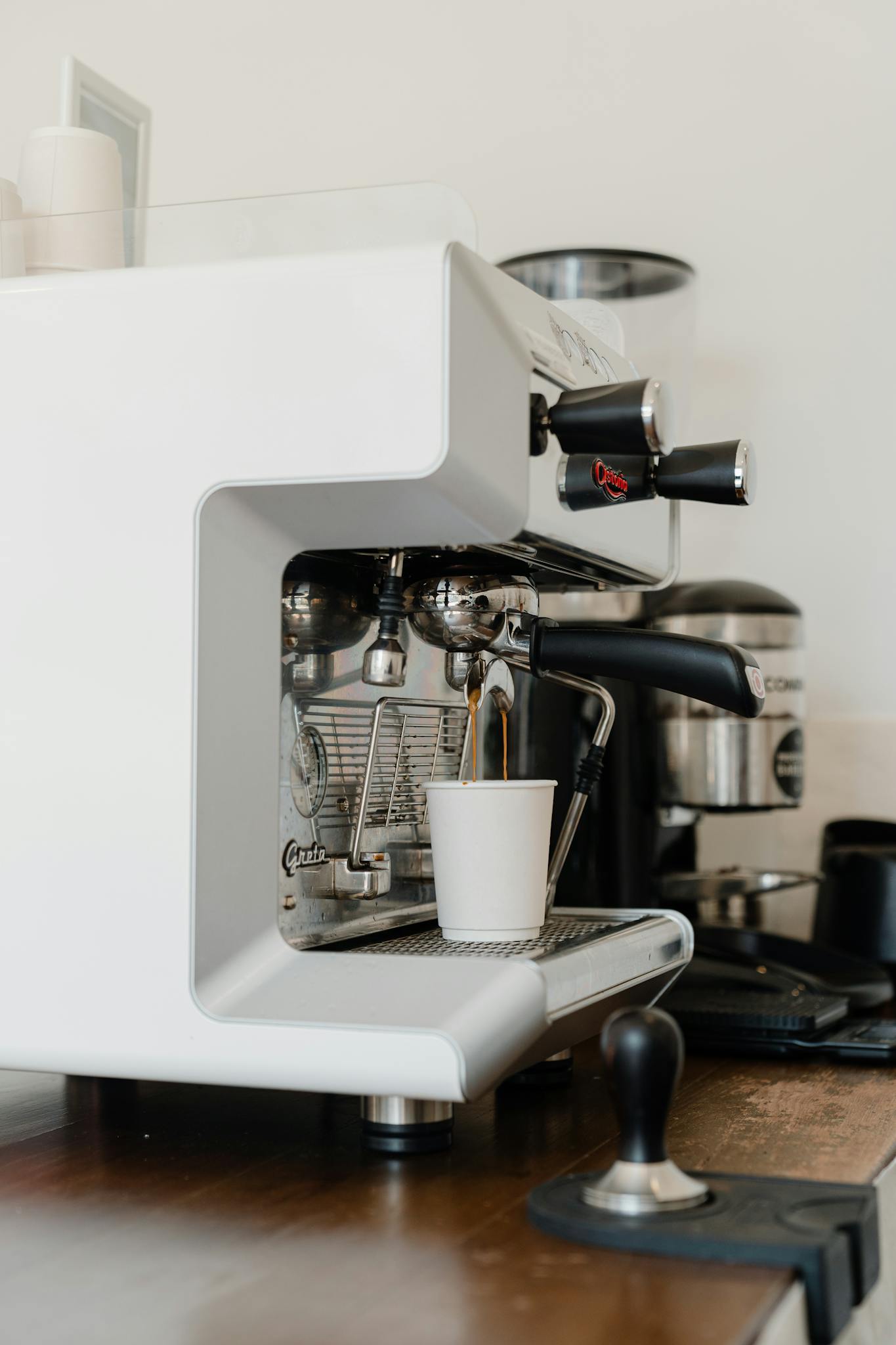 Professional coffee machine pouring coffee in paper cup